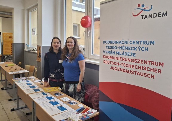 Tandem Mitarbeiterinnen stehen am Tandem Stand mit Infomaterialien