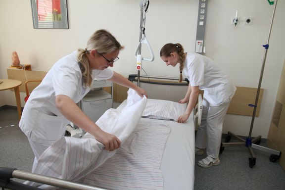 Junge Pflegekräfte trainieren, ein Krankenbett herzurichten