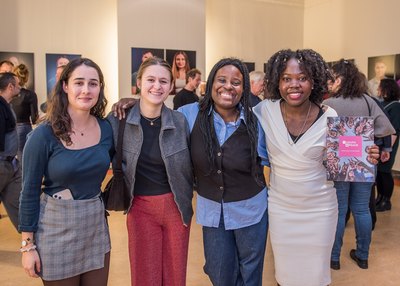 Junge Menschen auf einer Foto-Ausstellung stehen in einer Reihe