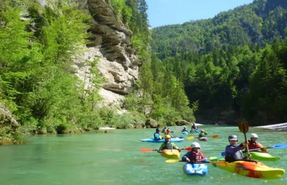 Kinder fahren mit Kanus auf einem Fluss.