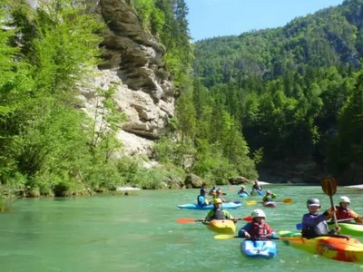 Kinder fahren mit Kanus auf einem Fluss.