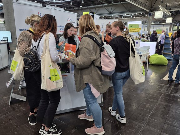 Eine Gruppe junger Frauen informiert sich an einem Messestand