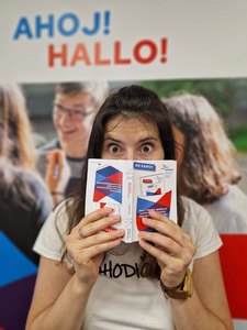 Eine Frau hält den deutsch-tschechischen Sprachführer Do kapsy in der Hand. Im Hintergrund ist ein Roll-Up mit dem Schriftzug Ahoj - Hallo zu sehen.