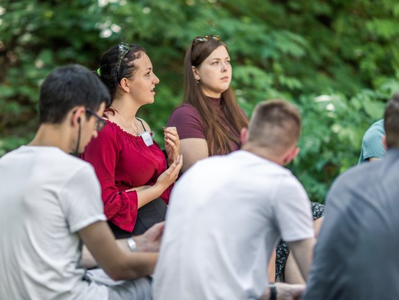 Ein Mädchen sitzt am Lagerfeuer und spricht
