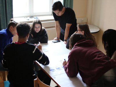 Junge Menschen sitzen um einen Tisch und diskutieren über ein Thema.