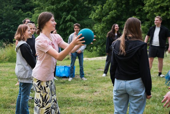 Junge Menschen spielen in einem Park mit einem Ball.