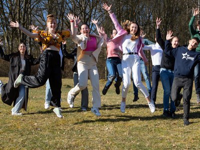 Junge Menschen hüpfen bei einem Jugendtreffen in die Luft.